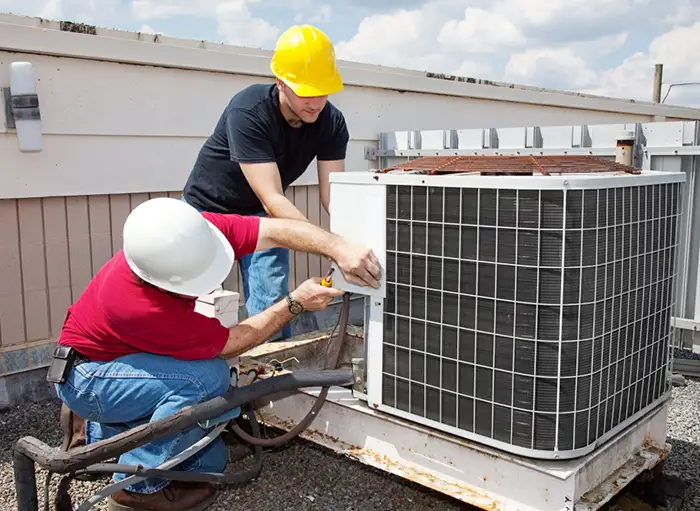 two hvac workers on the buliding fixing an heatpump